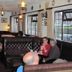 Guests seated in a cozy lounge at Green Acre Motel, Bridgend, with leather booths and hanging lamps.
