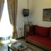 Gythion Hotel in Gytheio room with red sofa, small TV, wall art, and balcony curtains