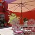 Hotel Camba Oaxaca courtyard with red walls, patio table, umbrella and wrought-iron chairs