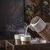 Villaki Oia in Oia: a hand pours steaming water from a cup into a tray of small cups
