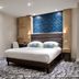 Serotel Suites Paris hotel room with king bed, patterned carpet, and blue headboard wall