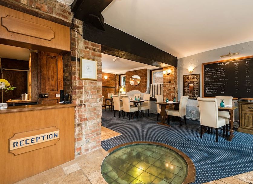 The Well guesthouse in Marlborough reception and dining area with brick walls, round glass floor feature, and seating