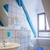 Hotel Vier Jahreszeiten bathroom in Volkach with wall-mounted sink, toilet, blue accents and window