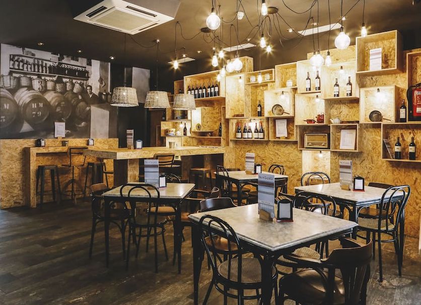 Hotel Piñupe in Lekeitio bar and dining area with tables, shelves of bottles, and warm hanging lights