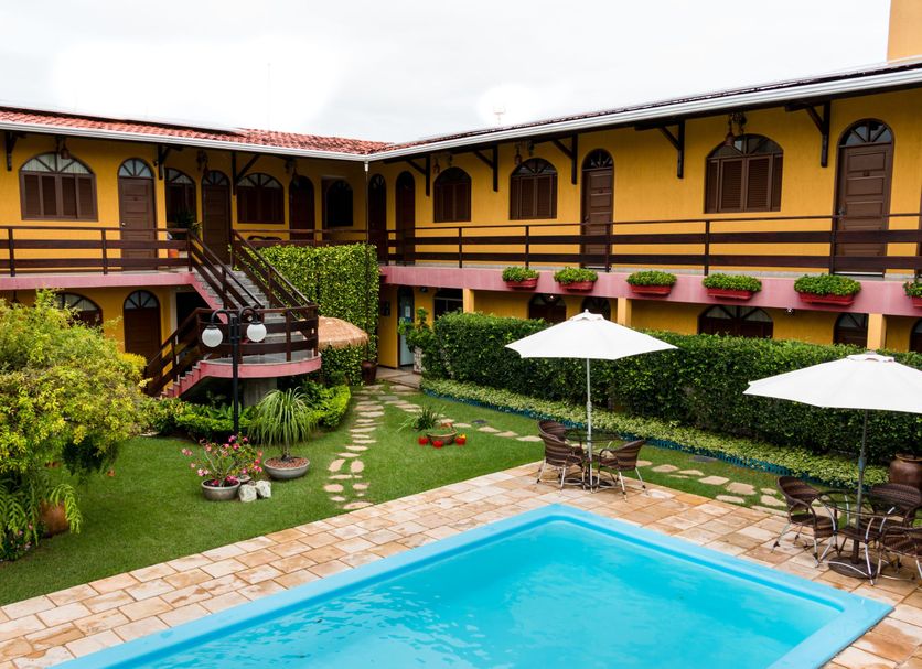 Pousada Da Terra in Natal with a courtyard pool, patio seating and yellow two-story building