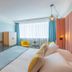 Golden Tulip Aix Les Bains room with double bed, desk, TV, wardrobe, and colorful chairs