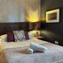 The Churchill Court Woodstock guest room with a neatly made bed, bedside lamps, and framed wall art.