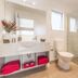 Mohua Motels Takaka bathroom with walk-in glass shower, toilet, sink, mirror, and red towels