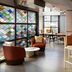 Moxy Asheville Downtown lobby bar with colorful stained-glass partition, seating, and tall stools in Asheville