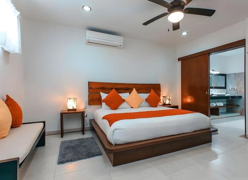 Casa Ticul Hotel By Bfh in Playa del Carmen: bedroom with king bed, orange accents, and ceiling fan