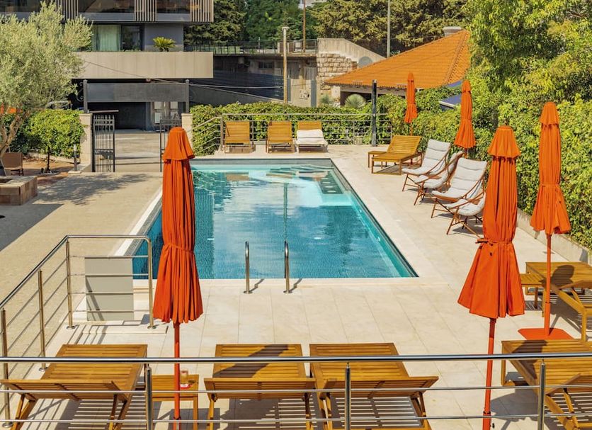 Hotel Aquarius Dubrovnik in Dubrovnik: outdoor pool with orange umbrellas and lounge chairs