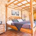 Agroturismo Es Quatre Cantons in Binissalem: four-poster bed in a stone guest room with terracotta tile floor.