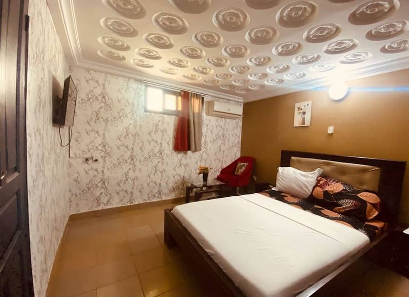 Residence Bethany Palace in Abidjan bedroom with bed, patterned ceiling, wall-mounted TV and window
