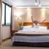 Gran Pacifico in Puerto Montt: guest stretching on bed in a bright hotel room with window and wood closet