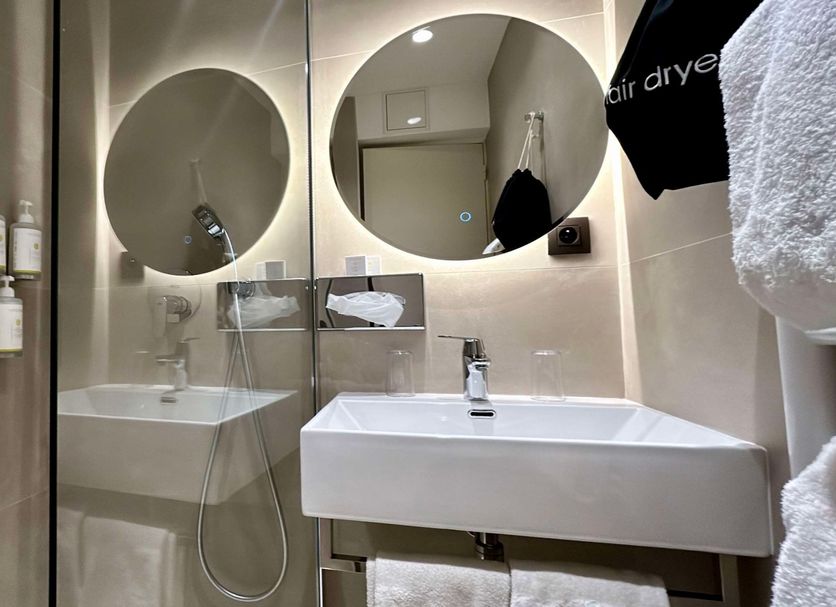 Best Western Plus Au Grand Saint Jean in Beaune bathroom with dual round mirrors and glass shower