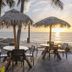 Ocean Breeze Inn Vero Beach oceanfront patio with thatched umbrellas and sunset sea views