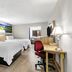 Days Inn by Wyndham Salina South room with two beds, desk, chair, and landscape wall art