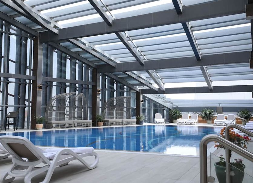 Vip Hotel in Doha indoor pool with lounge chairs and skylit glass roof