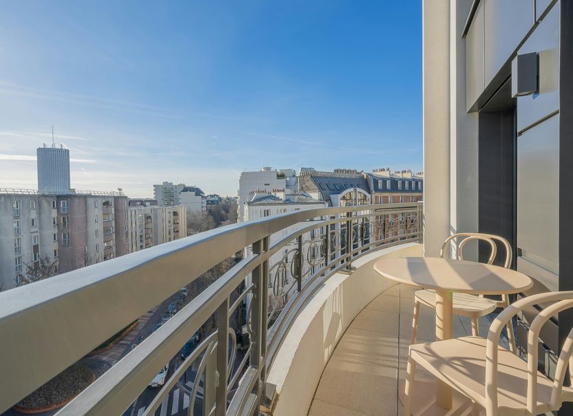 Yuna Porte-Maillot - Aparthotel in Paris: curved balcony with city skyline views and outdoor seating