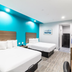 Scottish Inns & Suites - Kingwood in Humble guest room with two beds and turquoise accent wall