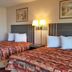 Scottish Inns Mcminnville room with two double beds, lamp, mirror and wall art in McMinnville
