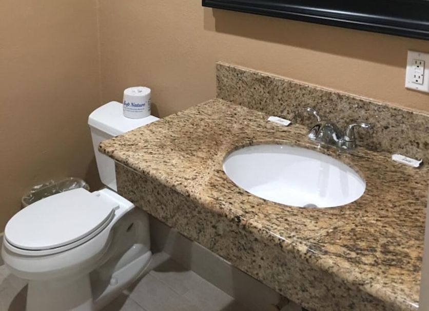 Budget Inn in Lawndale bathroom with granite vanity, mirror, toilet and tiled shower reflection