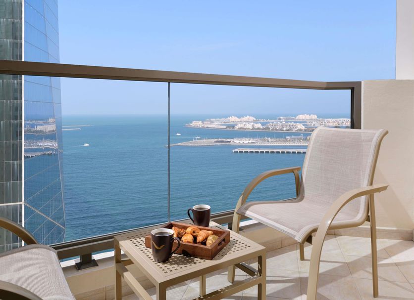 Mövenpick Hotel Jumeirah Beach balcony with chair, coffee and pastries overlooking Dubai sea and skyline
