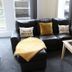 The Darnley Hotel, Ilfracombe: black leather sofa with yellow throw, side table and wall-mounted TV