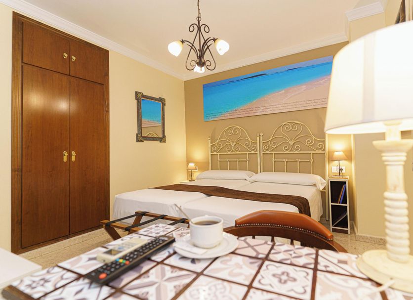 Hotel Colón, Ronda guest room with double bed, wardrobe, bedside lamps and beach mural