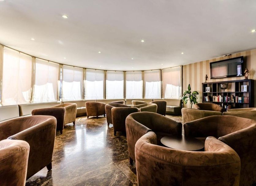 Alcala Plaza lounge in Alcalá de Henares with brown armchairs, TV, and large windows