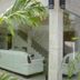 Hotel Tobiko, Trincomalee: glass-walled lounge with white sofa and staircase visible behind palm leaves