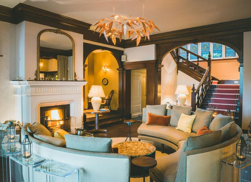 The Coed-Y-Mwstwr Hotel in Bridgend lounge with fireplace, curved sofas, chandelier and staircase