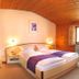 Gästehaus Enzianhof Hotel Garni in Oberammergau: cozy room with bed, armchair, and curved wood ceiling