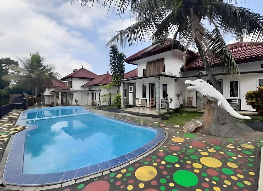 Seulawah Resort And Cafe in Batu with outdoor pool, palm trees, and a dolphin sculpture by the patio