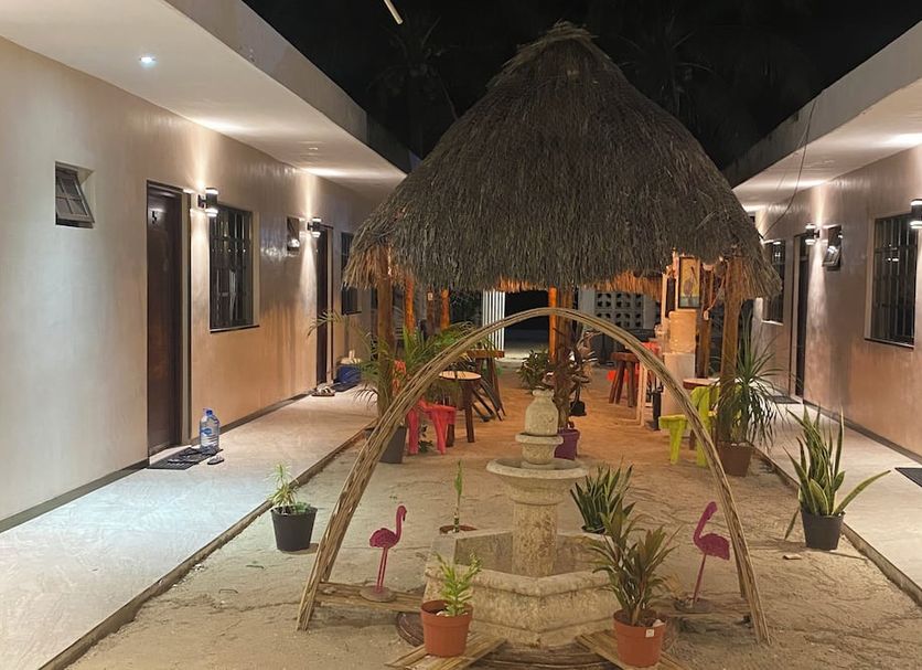 Hotel San Julio in Celestún courtyard with thatched palapa, sand walkway, and flamingo decor