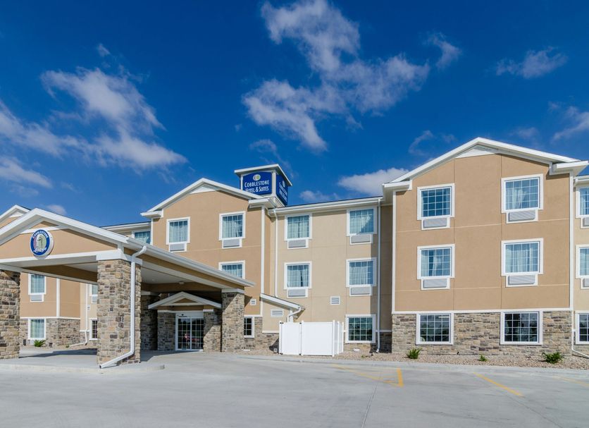 Cobblestone Hotel & Suites - Mccook exterior with covered entrance under a blue sky