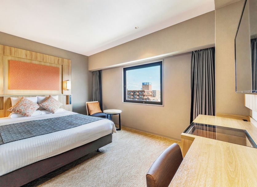 Art Hotel Morioka guest room with bed, window city view, desk and chair in Morioka