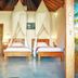 Three Monkeys Villas, South Kuta: twin canopy beds in a bright villa room with open doors to the outside.