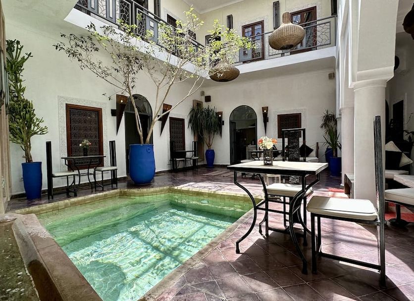 Riad Jardin Des Rêves in Marrakech courtyard pool with tables, potted trees, and upstairs balcony