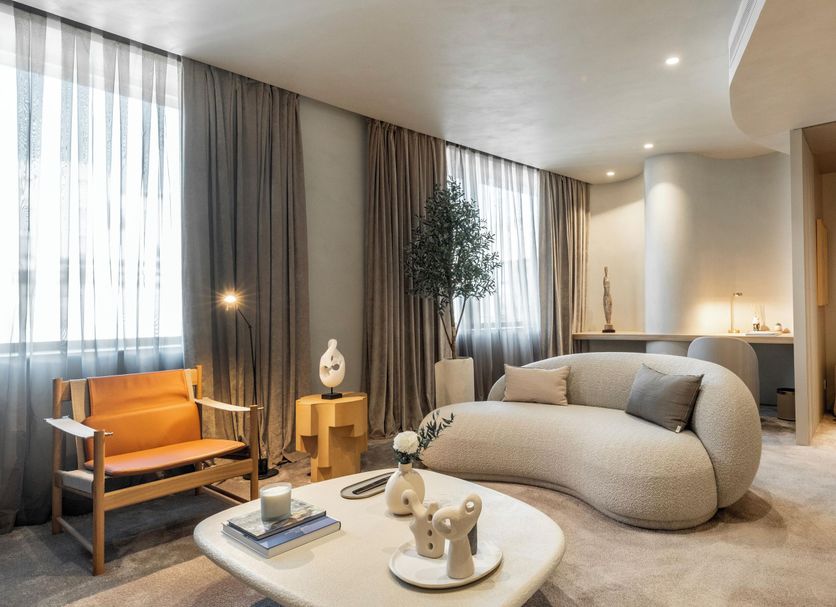 Carlemany Girona in Girona: modern guest lounge with sculptural sofa, lounge chair, coffee table and tall windows.