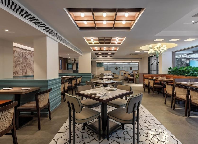 Hotel Suncity Residency Mumbai restaurant dining area with tables, chairs, and ceiling lights