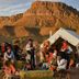 Grand Canyon Western Ranch in Meadview with guests by a tent and horses before desert cliffs