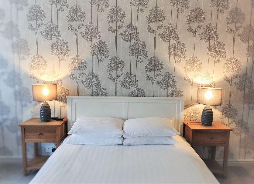 Woodcote Hotel in Ellesmere Port bedroom with double bed, matching bedside lamps and patterned wallpaper