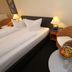 Hotel Lindemann, Bad Nauheim guest room with twin bed, wicker chair and small table with fruit and flowers