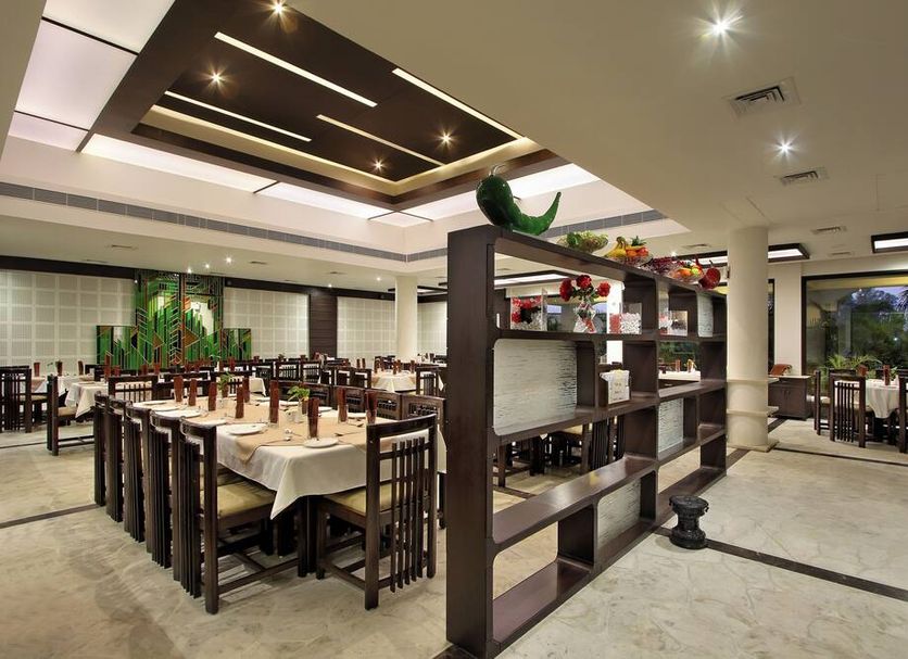 Prakruti Resort in Vadodara restaurant dining area with set tables, chairs, and shelving divider