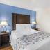 SureStay Plus by Best Western Niagara Falls East room with king bed, blue accent wall and bedside lamps
