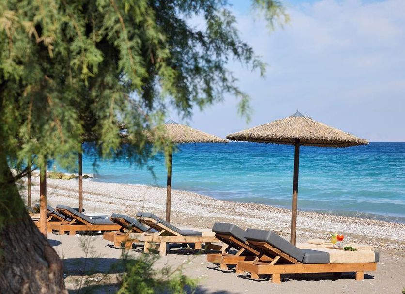 Labranda Blue Bay Resort in Ialysos with beach loungers and thatched umbrellas by the sea