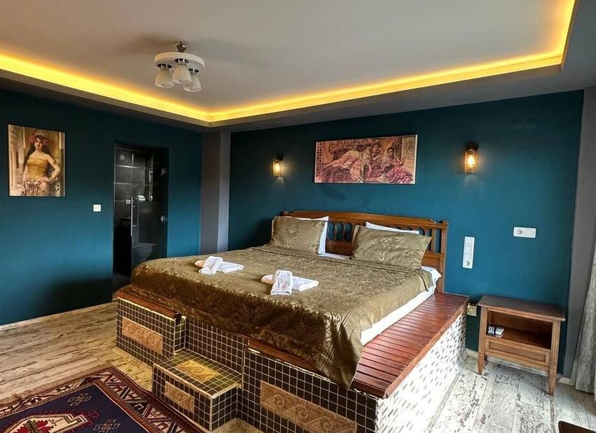 Rebetika Hotel Selçuk room with king bed, dark teal walls, ceiling lights, and patterned rug