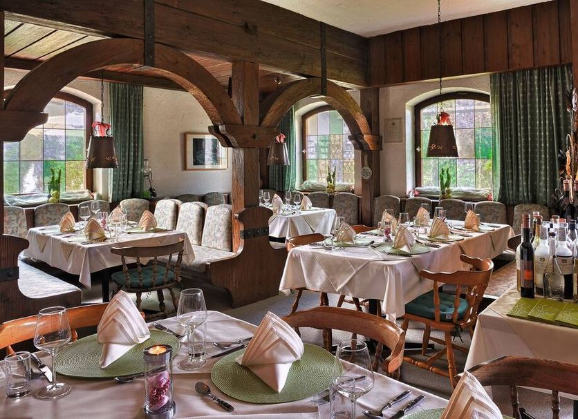 Landhotel Binderhäusl Garni dining room in Inzell with set tables, wood beams, and arched windows