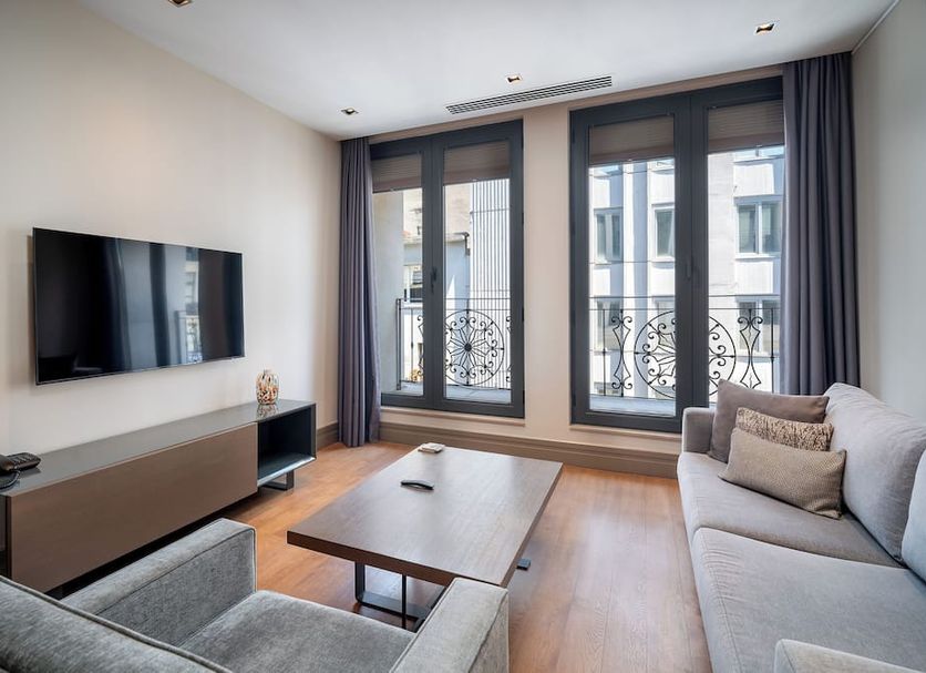 Sentire Hotels & Residences Taksim living room with sofa, TV, coffee table and city-view windows in Istanbul